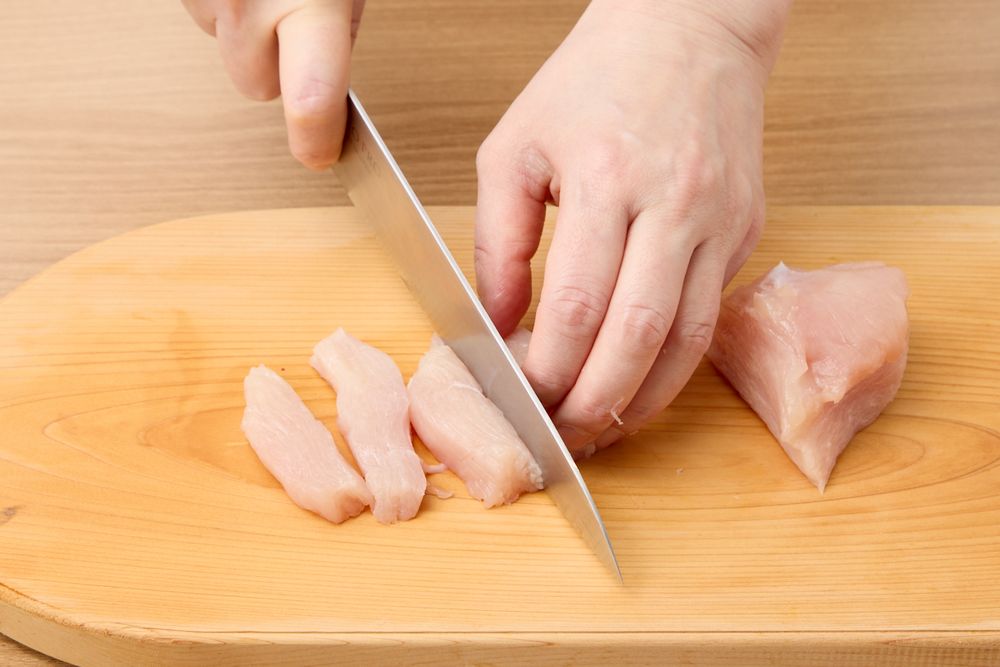 鶏むね肉を棒状に切っているところ