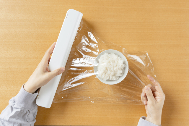 食品用のラップを用いてご飯を保存する女性