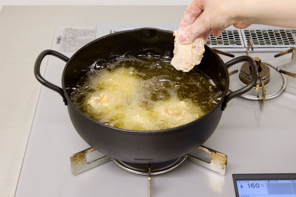 揚げ鍋に唐揚げを入れているところ