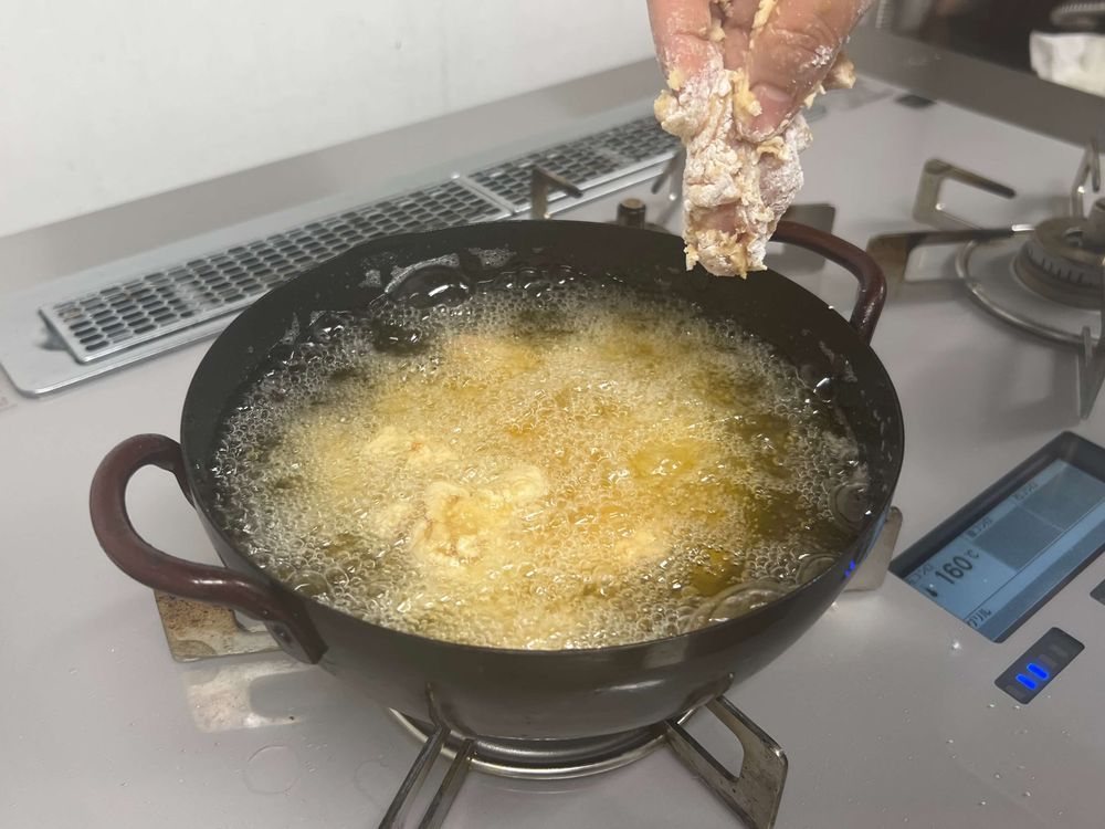 唐揚げを揚げ鍋に投入する様子
