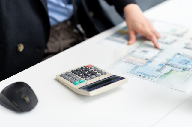 建築資料を見ながら計算する女性の手元
