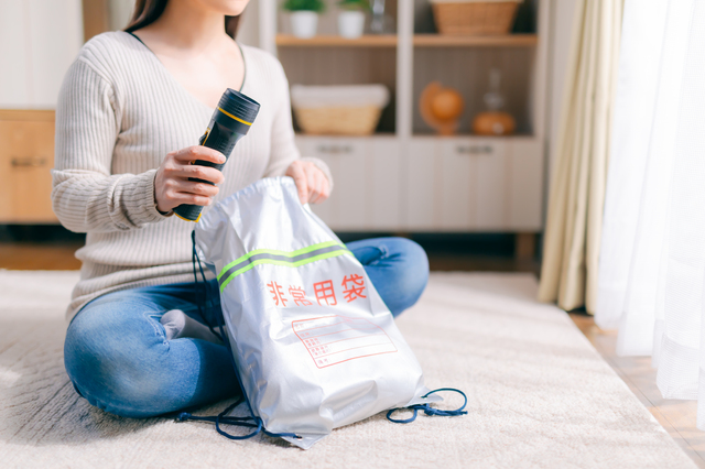 非常用バッグに懐中電灯を入れる女性
