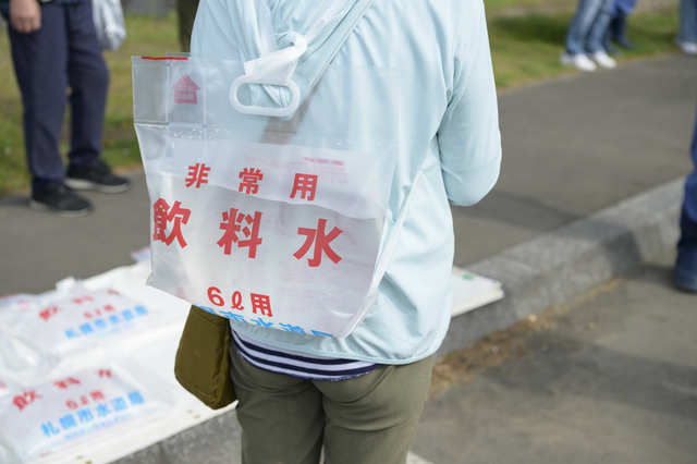 非常用飲料紙袋を背負う人物