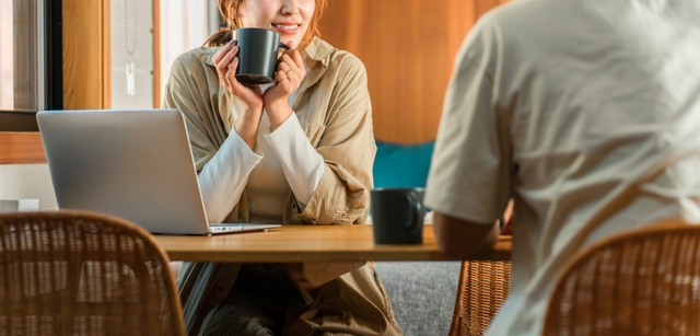 コテージでパソコンをやりながらコーヒーを飲む夫婦